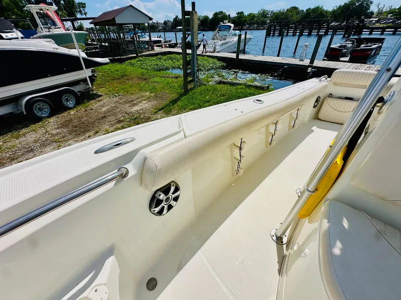 Slide: The Image of 2014 Mako 204 CC boat interior with rod holders and speaker, dockside view. - 19