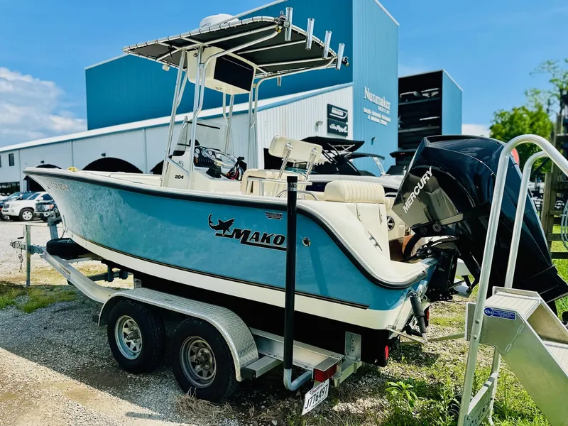 Slide: The Image of 2014 Mako 204 CC boat on trailer, parked outdoors near a blue building. - 4