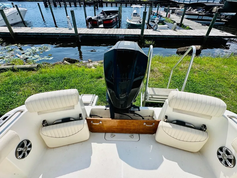 Slide: The Image of 2014 Mako 204 CC boat with outboard motor, docked by a lakeside pier. - 9