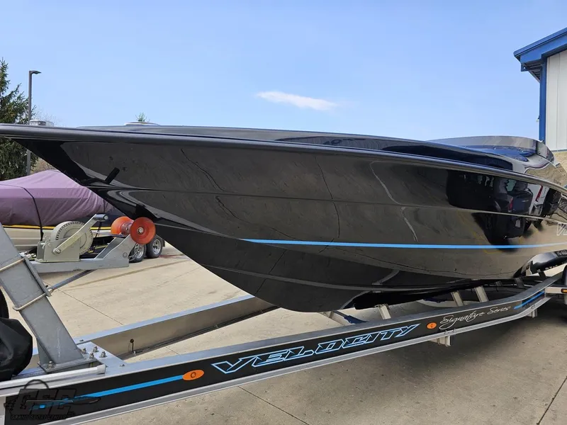 Slide: The Image of 2022 Velocity 290SC Signature Series boat on trailer, sleek black design with blue accents. - 18