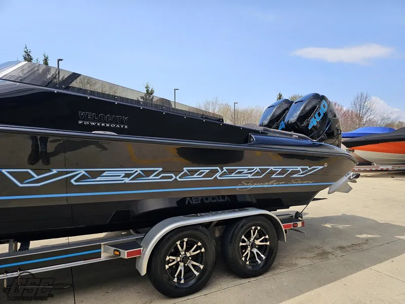 Slide: The Image of 2022 Velocity 290SC Signature Series boat on trailer, sleek black design with blue accents. - 21