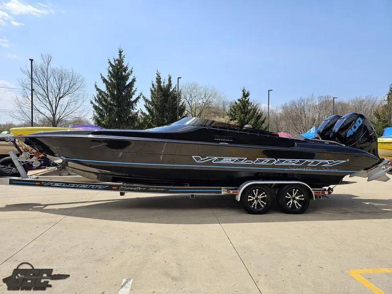 Slide: The Image of 2022 Velocity 290SC Signature Series boat on trailer, sleek black design, parked outdoors. - 24