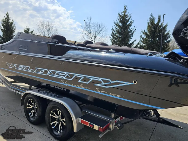 Slide: The Image of 2022 Velocity 290SC Signature Series boat on trailer, sleek black design, parked outdoors. - 26