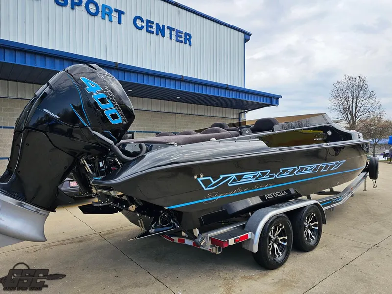 Slide: The Image of 2022 Velocity 290SC Signature Series boat on trailer outside sport center. - 9