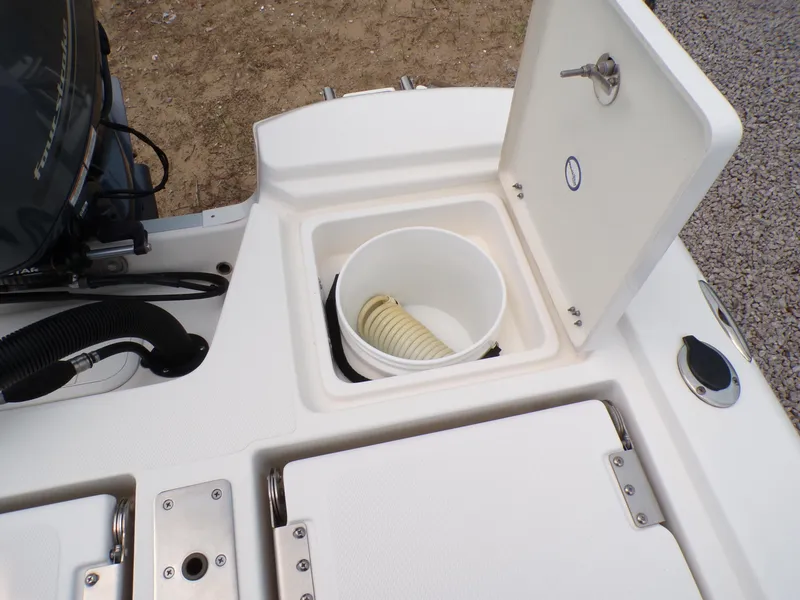 Slide: The Image of 2023 NauticStar 227 XTS boat storage compartment with hose and bucket. - 27