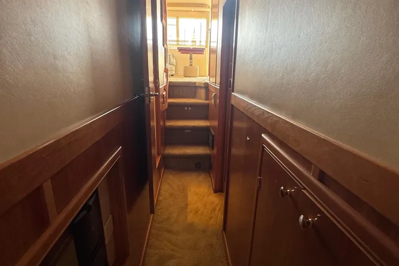 Slide: The Image of Hallway inside 2004 Meridian 490 Pilothouse yacht, featuring wooden cabinetry and carpeted flooring. - 14