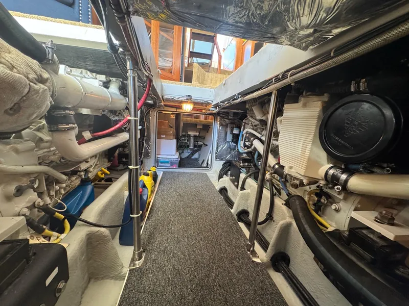 Slide: The Image of Engine room of 2004 Meridian 490 Pilothouse yacht, showcasing mechanical components and walkway. - 20