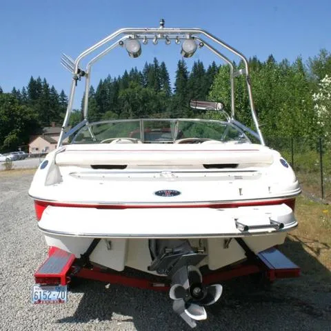 Slide: The Image of 2000 Chaparral 186 SSi boat, rear view, parked on gravel, surrounded by trees. - 4