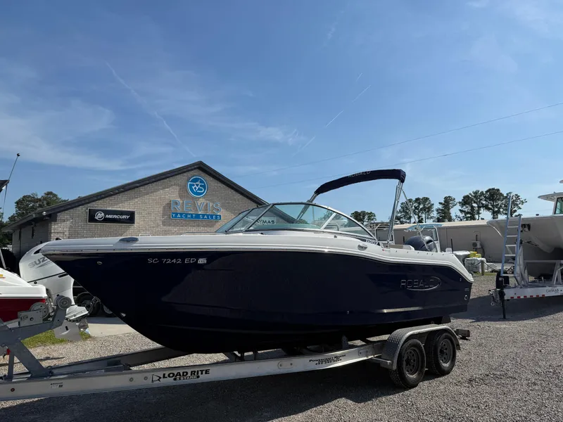 The Image of 2024 Robalo R207 Dual Console boat on trailer, parked outdoors under clear sky. - 1
