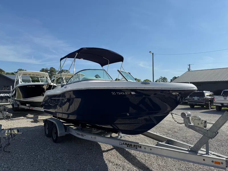 Slide: The Image of 2024 Robalo R207 Dual Console boat on trailer, parked outdoors under clear sky. - 10