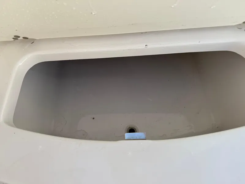 Slide: The Image of 2024 Robalo R207 Dual Console storage compartment, white interior, open lid. - 22