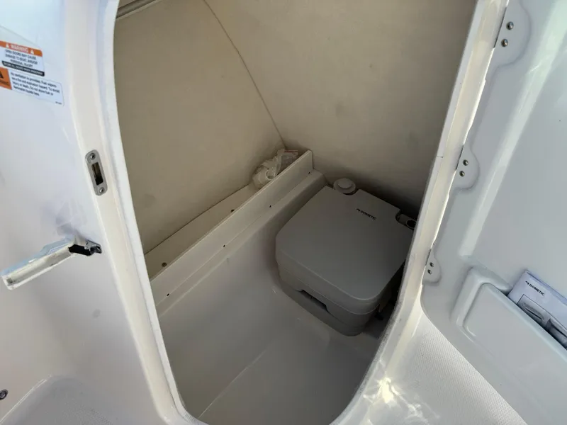 Slide: The Image of 2024 Robalo R207 Dual Console boat interior with compact marine toilet. - 23