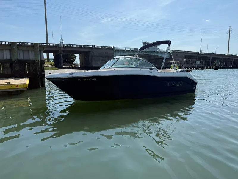 Slide: The Image of 2024 Robalo R207 Dual Console boat on water near a bridge. - 33