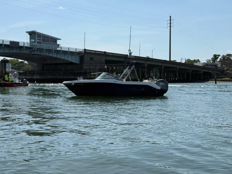 Slide: The Image of 2024 Robalo R207 Dual Console boat on water near a bridge. - 36