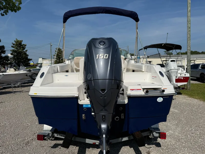 Slide: The Image of 2024 Robalo R207 Dual Console boat with 150 HP engine, parked on gravel. - 6