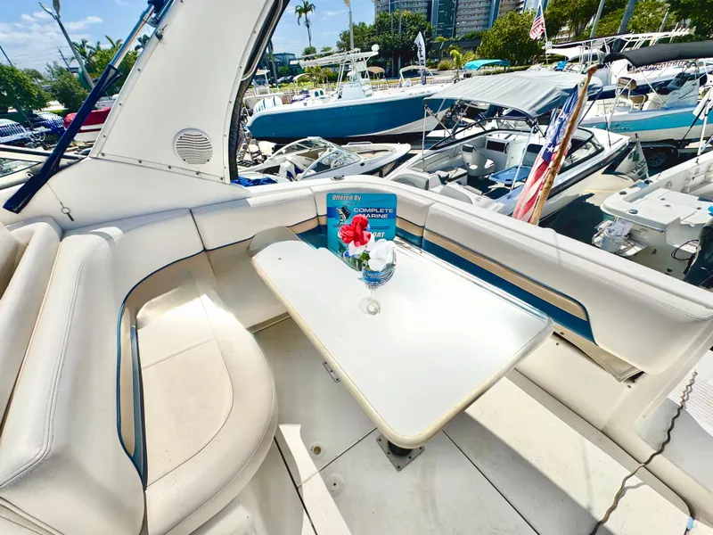 Slide: The Image of 1999 Chaparral 290 Signature Cruiser interior with seating and table, docked at a marina. - 10