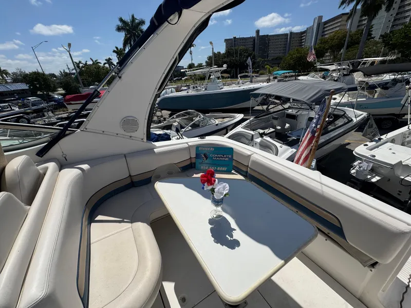 Slide: The Image of 1999 Chaparral 290 Signature Cruiser interior with table, flower vase, and marina view. - 13