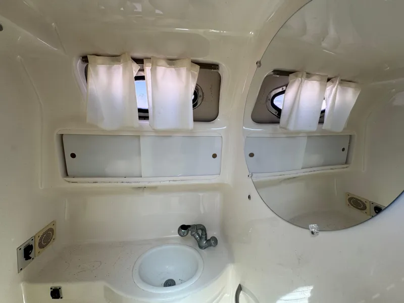 Slide: The Image of 1999 Chaparral 290 Signature Cruiser bathroom with sink, mirror, and porthole windows. - 19