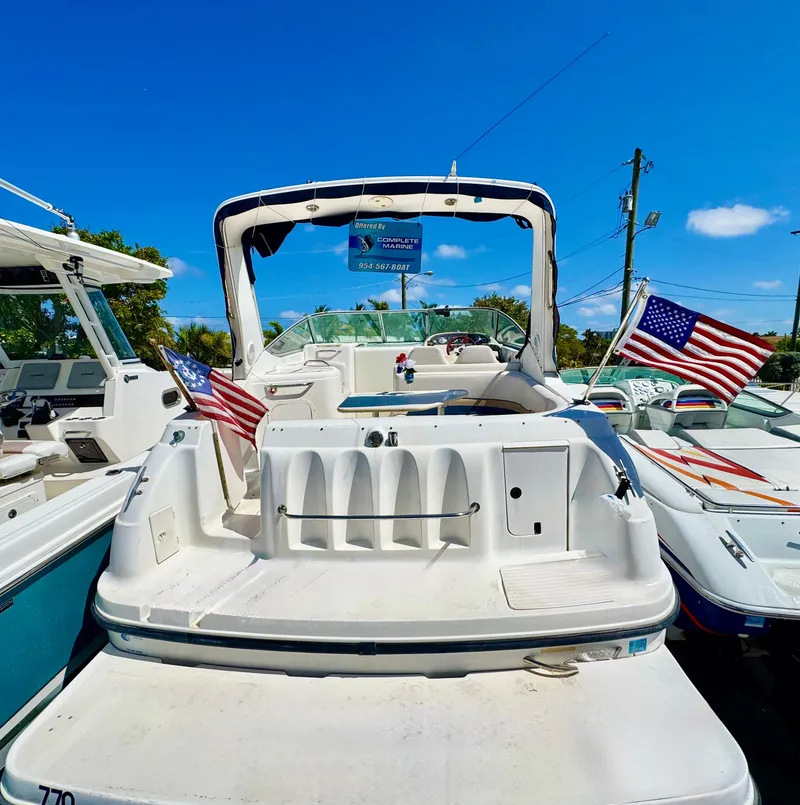 Slide: The Image of 1999 Chaparral 290 Signature Cruiser with American flags, docked under a clear blue sky. - 2