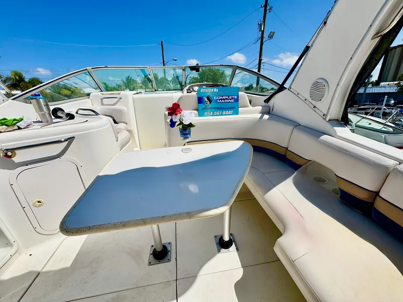Slide: The Image of 1999 Chaparral 290 Signature Cruiser interior with seating and table, under clear blue sky. - 20