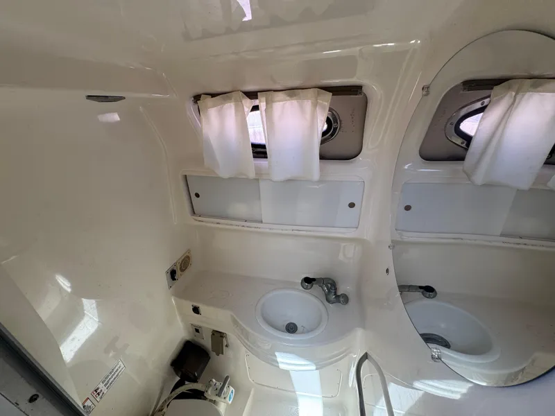 Slide: The Image of 1999 Chaparral 290 Signature Cruiser bathroom with sink, mirror, and porthole windows. - 21