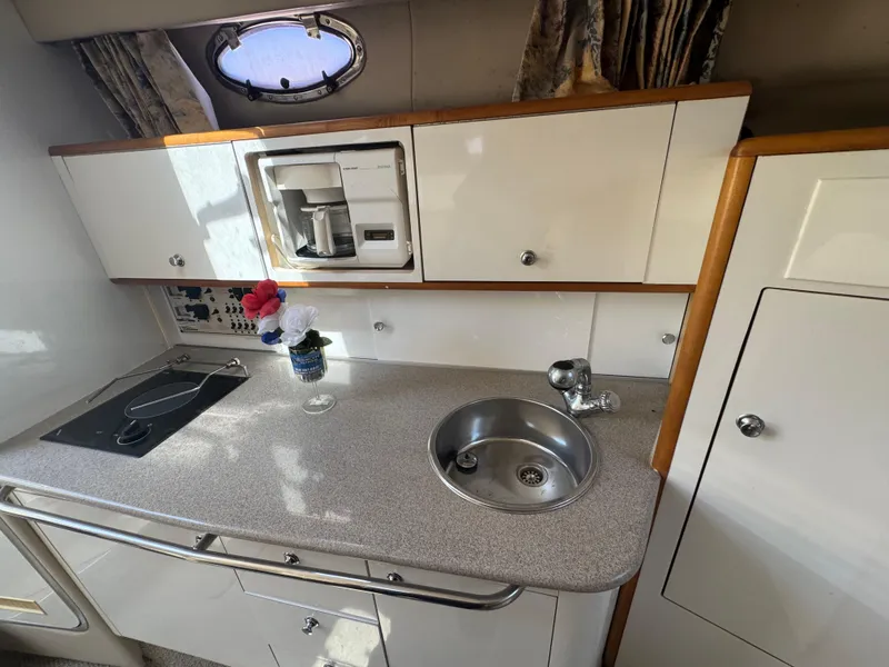 Slide: The Image of 1999 Chaparral 290 Signature Cruiser kitchen with sink, stove, and storage cabinets. - 25