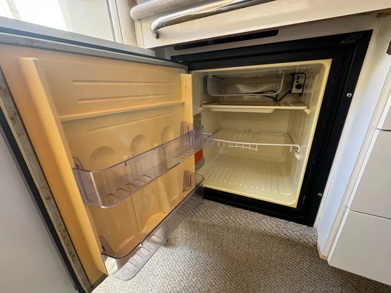 Slide: The Image of Open refrigerator inside a 1999 Chaparral 290 Signature Cruiser, showing interior shelves and door storage. - 29