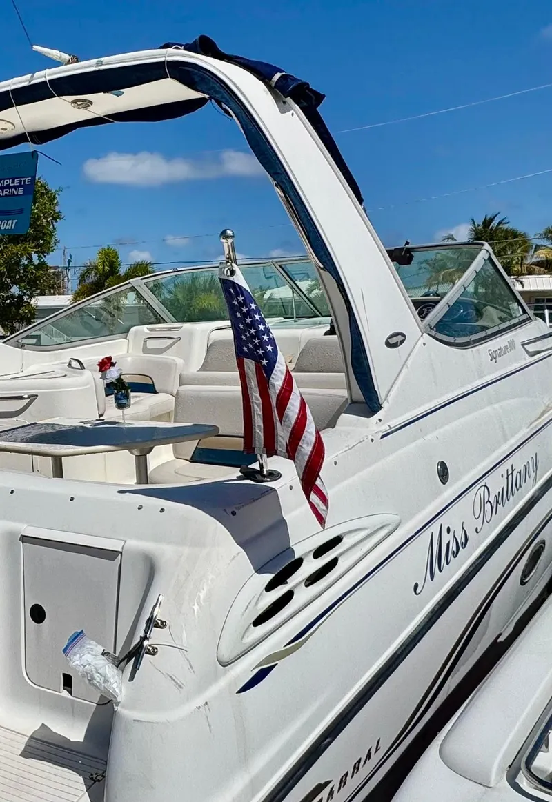 Slide: The Image of 1999 Chaparral 290 Signature Cruiser with American flag, docked under clear blue sky. - 3