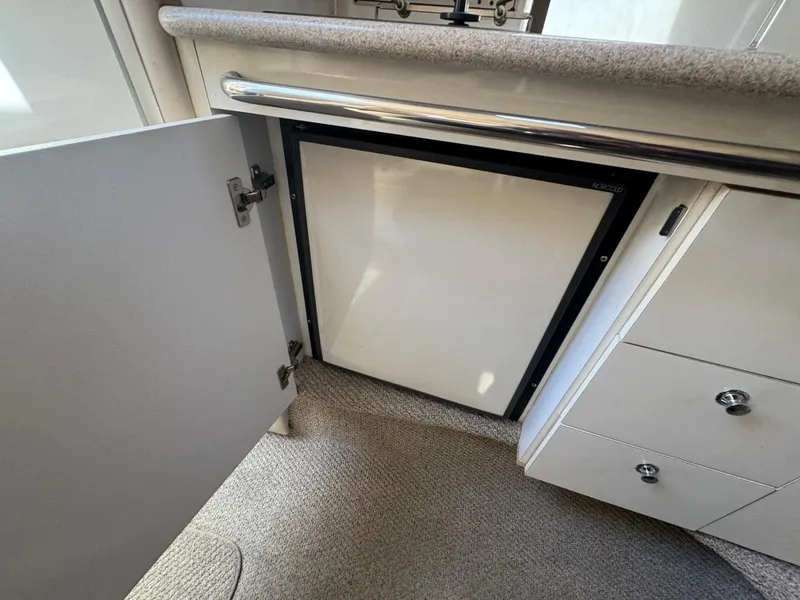 Slide: The Image of 1999 Chaparral 290 Signature Cruiser interior with open cabinet and compact refrigerator. - 30