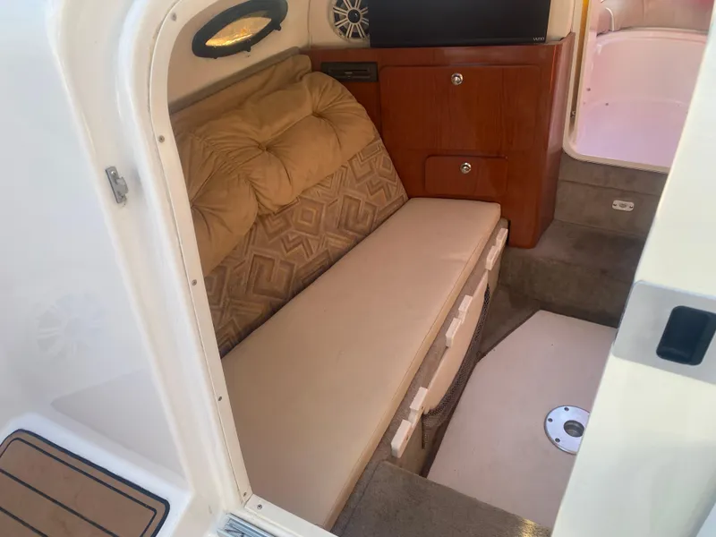 Slide: The Image of 2011 Ebbtide 2700 Cuddy Bow Rider interior with cushioned seating and wooden cabinetry. - 11