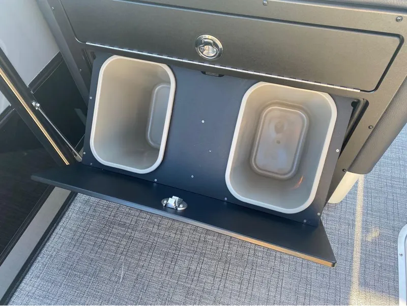 Slide: The Image of 2024 Trifecta 23 RFS 3.0 boat storage compartment with dual bins, open view. - 27