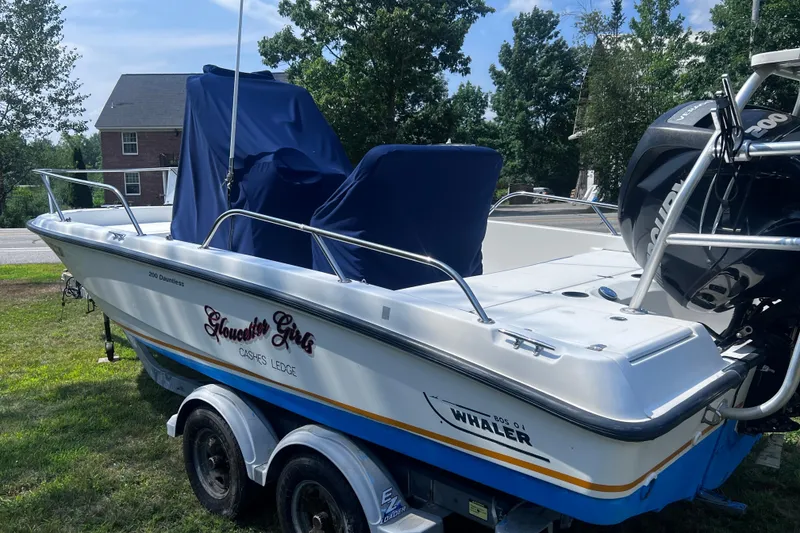 Slide: The Image of 2009 Boston Whaler 200 Dauntless boat on trailer, parked on grass, with covered seats. - 19