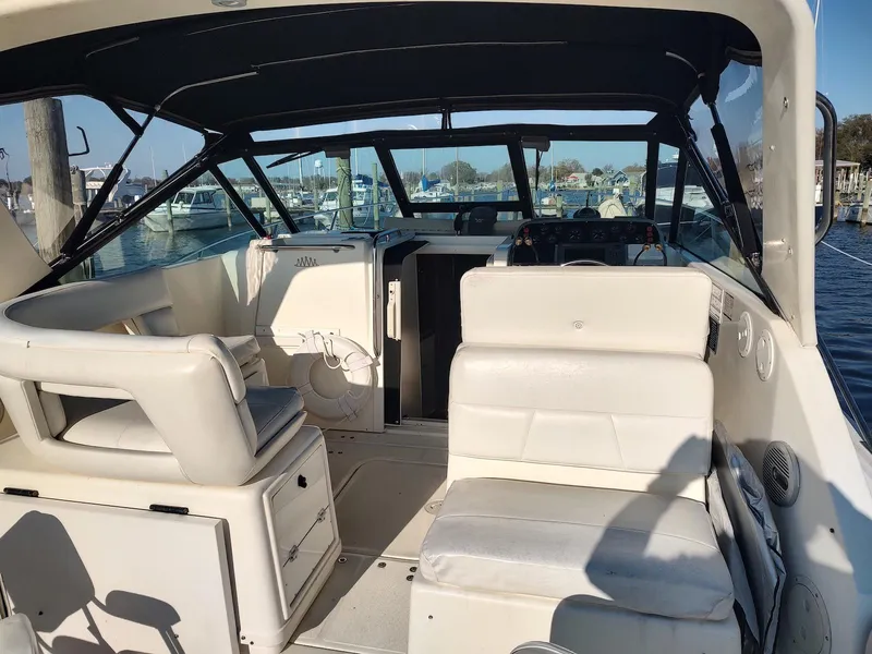 Slide: The Image of 1994 Tiara Yachts 3100 Open interior with white seating and helm, docked at marina. - 10