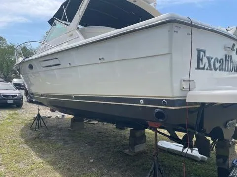 Slide: The Image of 1994 Tiara Yachts 3100 Open boat on stands, named "Excalibur," in a yard setting. - 23