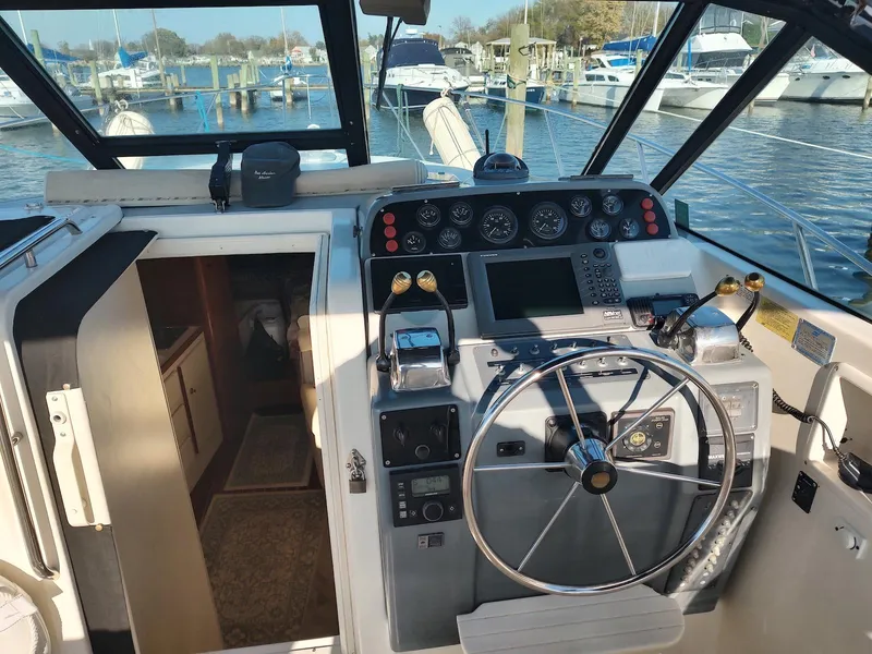 Slide: The Image of 1994 Tiara Yachts 3100 Open cockpit with steering wheel and control panel, docked at marina. - 6