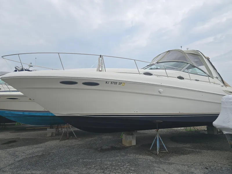 Slide: The Image of 2002 Sea Ray 340 Sundancer boat on stands, side view, cloudy sky background. - 1