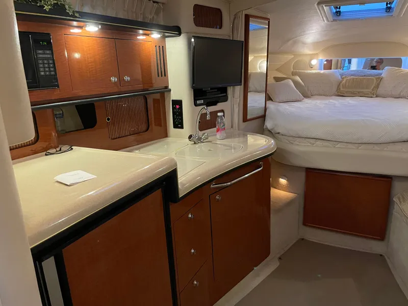 Slide: The Image of Interior of 2002 Sea Ray 340 Sundancer yacht with kitchenette and cozy sleeping area. - 15
