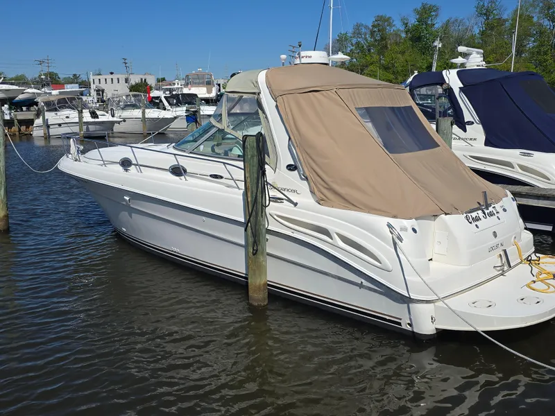 Slide: The Image of 2002 Sea Ray 340 Sundancer docked at marina, featuring beige canopy and sleek design. - 23