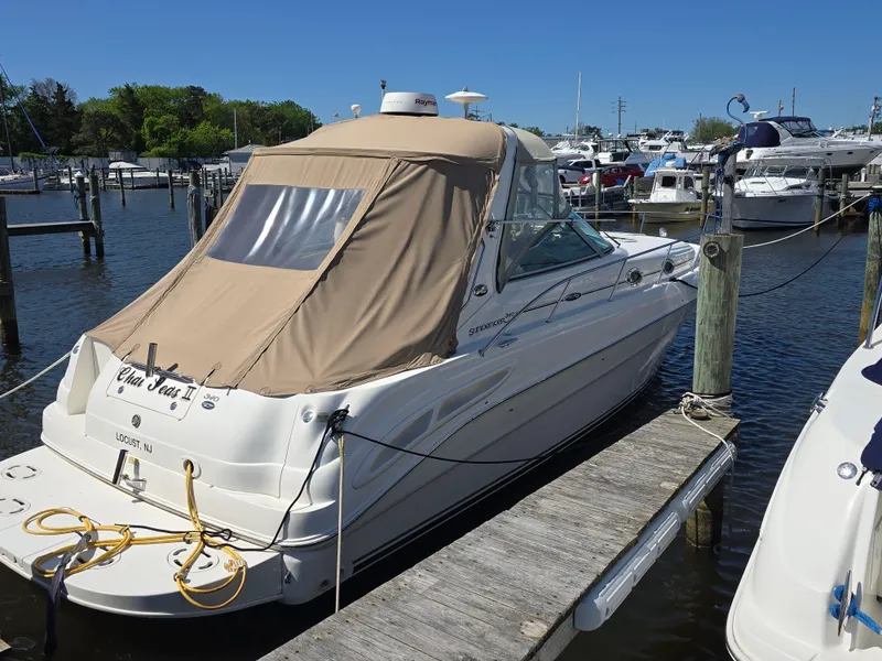 Slide: The Image of 2002 Sea Ray 340 Sundancer docked at marina, featuring beige canopy and sleek design. - 24