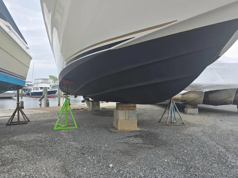 Slide: The Image of 2002 Sea Ray 340 Sundancer boat on stands, hull view, in a marina setting. - 3