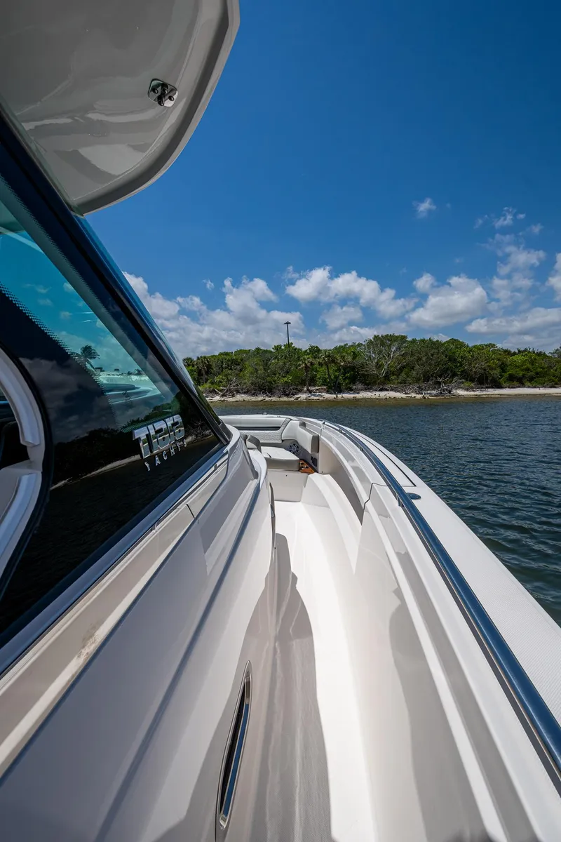 Slide: The Image of 2024 Tiara Yachts 38 LS cruising near a scenic shoreline under a clear blue sky. - 17