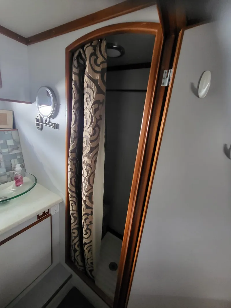 Slide: The Image of 1997 McKinna 48' Pilot House bathroom with shower and patterned curtain. - 17