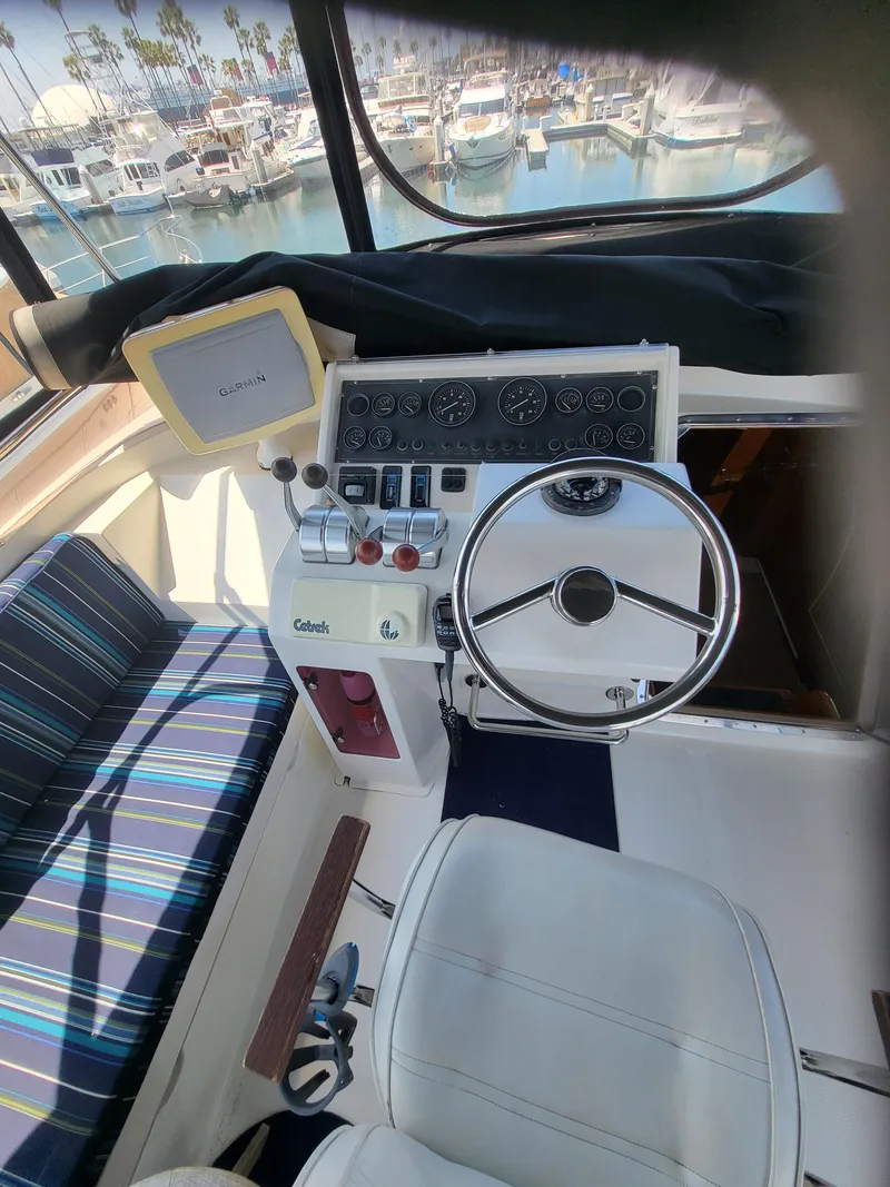 Slide: The Image of 1997 McKinna 48' Pilot House helm with steering wheel, controls, and marina view. - 19