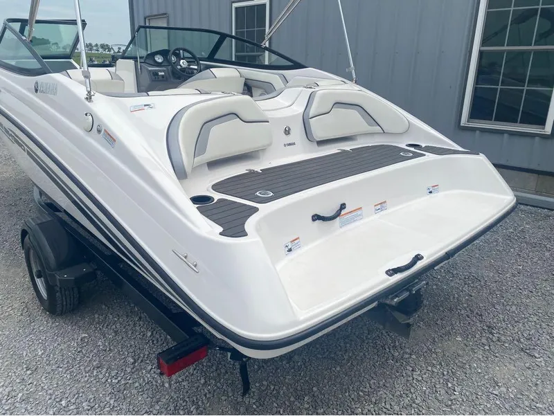 Slide: The Image of 2017 Yamaha Boats SX190 on trailer, white exterior, parked near building. - 2