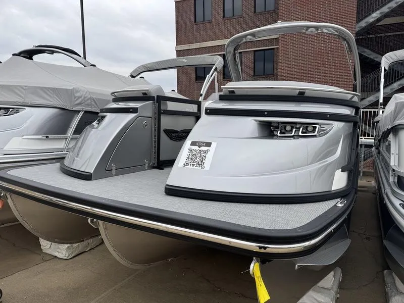 Slide: The Image of 2025 Bennington 25 QFBA pontoon boat with sleek design, docked near a brick building. - 0