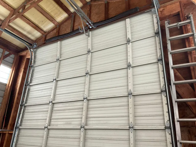 Slide: The Image of Large garage door inside a wooden boathouse, Custom model, 1987, with adjacent ladder. - 3