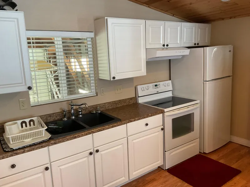 Slide: The Image of Compact kitchen in a 1987 custom boathouse with white cabinets and modern appliances. - 6