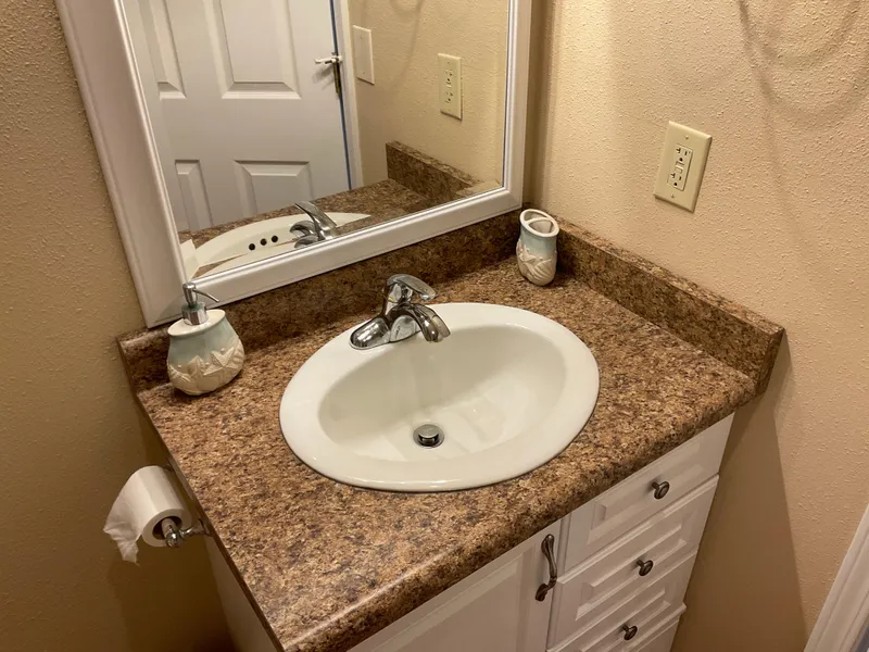 Slide: The Image of Bathroom sink with marble countertop, mirror, and soap dispenser in a 1987 Custom Boathouse. - 8