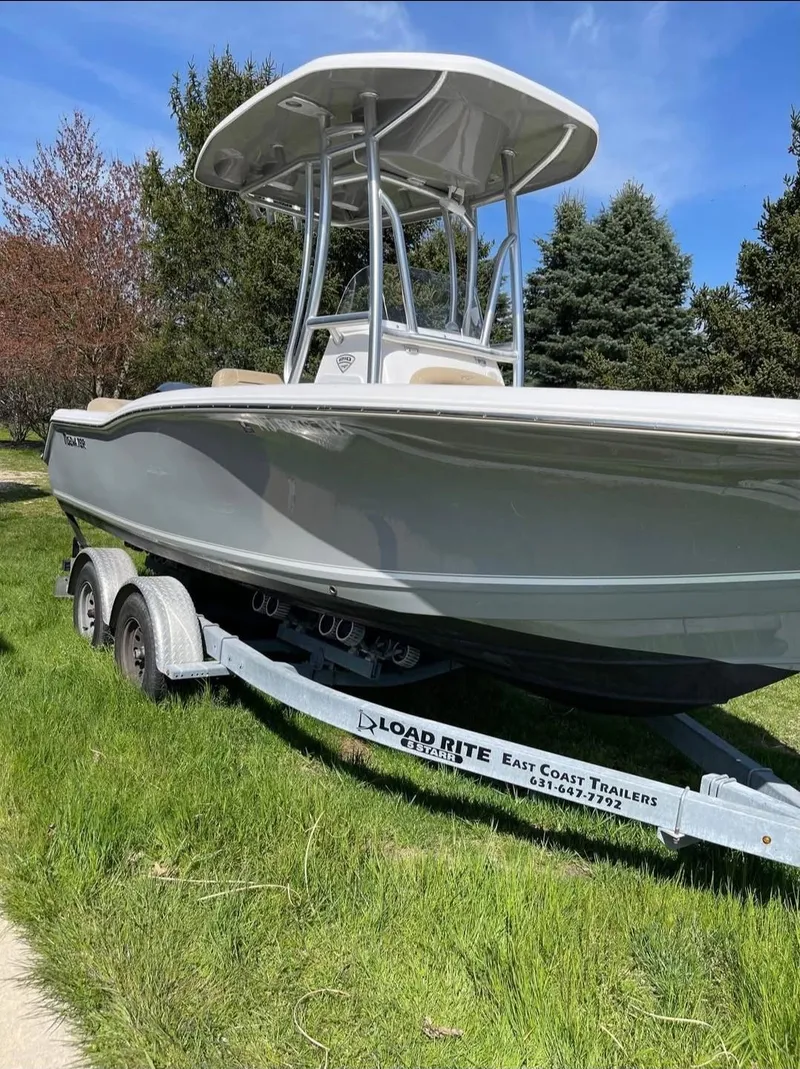 Slide: The Image of 2016 Tidewater 210 LXF boat on trailer, parked on grass, under clear blue sky. - 1