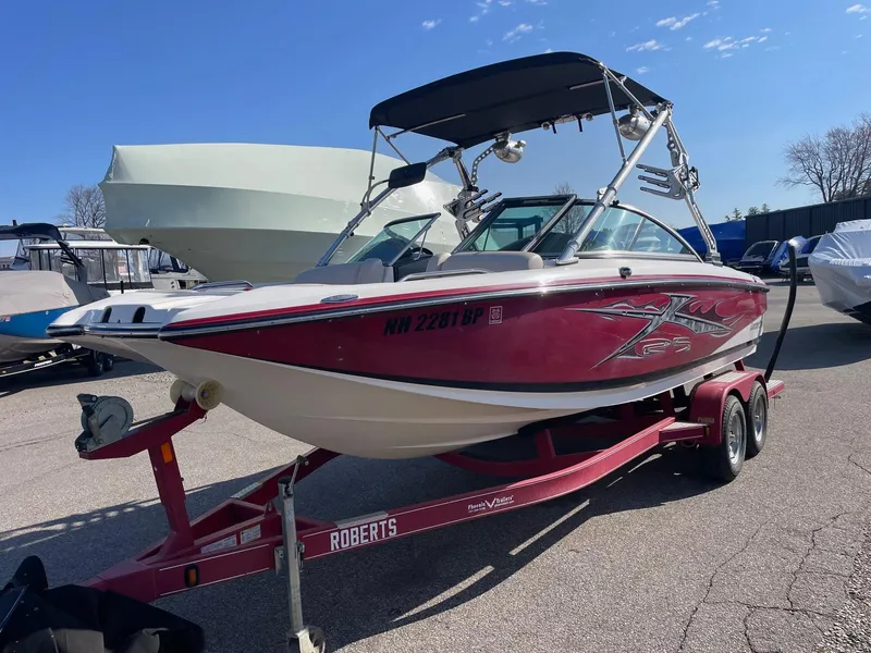 Slide: The Image of 2010 MasterCraft X-25 boat on a red trailer in a marina. - 0
